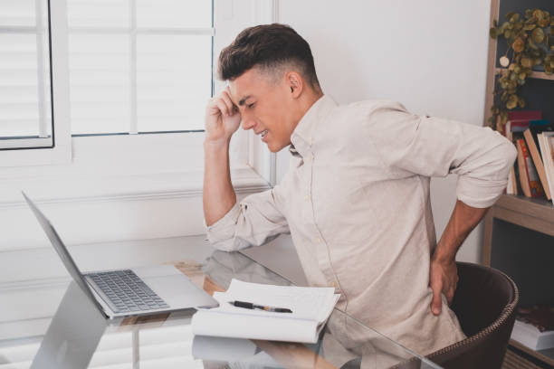 istock Close up rear view stressed young man touching lower back feeling discomfort, suffering from sudden pain due to sedentary lifestyle or long computer overwork in incorrect posture at home office. 1372303883