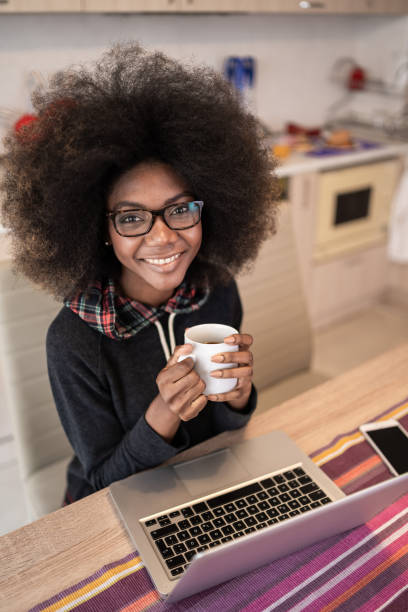 istock Afro Woman using laptop at home and drinking coffee 1372304869