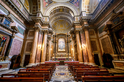 A suggestive view of the central nave and the main altar inside the church of the Santissima Trinità dei Pellegrini (Church of the Most Holy Trinity of the Pilgrims), in the historic and baroque heart of Rome. Located between Piazza Farnese and Ponte Sisto, in the Rione Regola (Regola district), this place of Catholic worship was built in the Baroque style between 1587 and 1616, hosting the brotherhood of charity founded by San Filippo Neri. In the background, above the main altar, a painting on wood of 1625 by Guido Reni and depicting the Holy Trinity. In 1980 the historic center of Rome was declared a World Heritage Site by Unesco. Super wide angle image in high definition format.