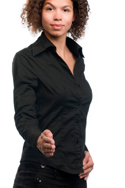 Happy businesswoman reaching hand for handshake. Portrait of cheerful young businesswoman greeting someone and smiling at camera. Handshake concept. Focus on hand.