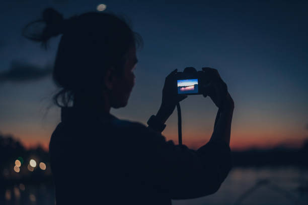 mujer joven usando una cámara con poca luz - low key lighting flash fotografías e imágenes de stock