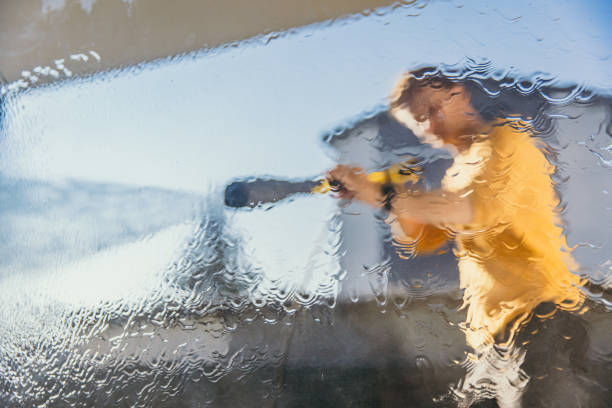 Man cleaning the window with high pressure cleaner on sunny day.