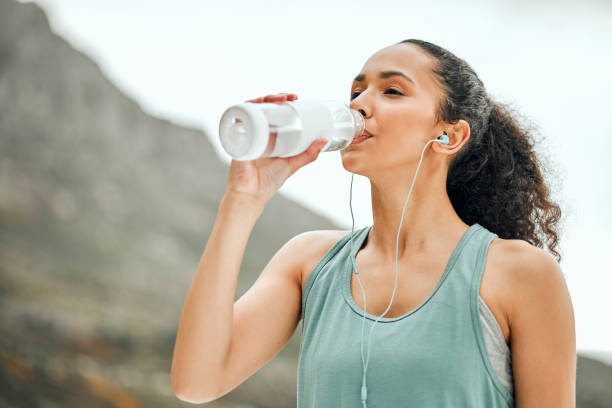 scatto di una giovane donna che si prende una pausa dall'allenamento per bere acqua - salutare foto e immagini stock