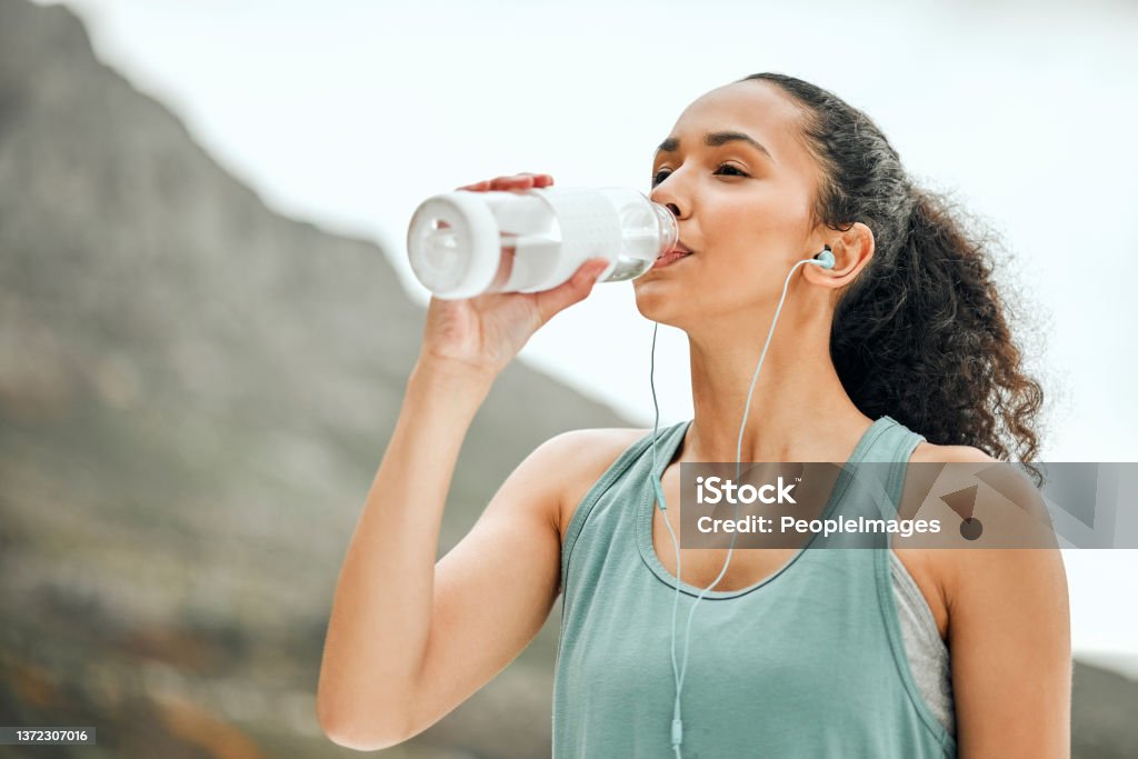 Shot of a young woman taking a break from working out to drink water Taking a break to re hydrate Drinking Stock Photo