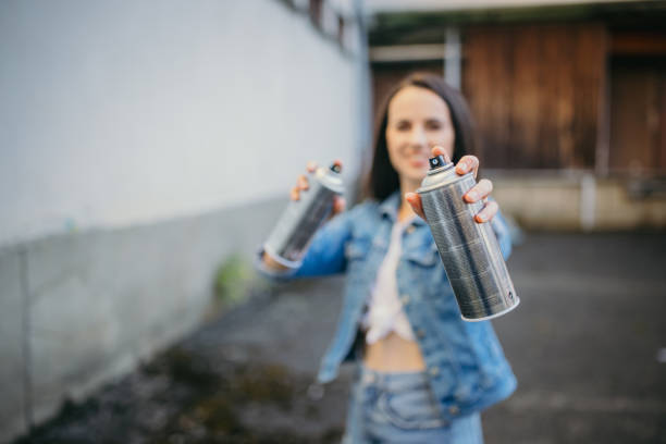 Beautiful young woman holding aerosol paint cans