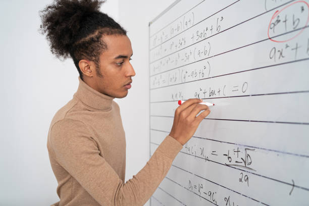istock An African male teacher in an empty classroom writing on whiteboard 1372307726