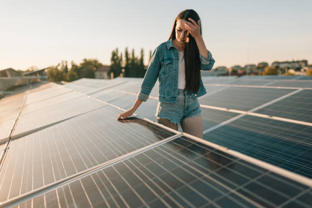 giovane donna che tocca i pannelli solari ai pannelli solari - denim shorts foto e immagini stock