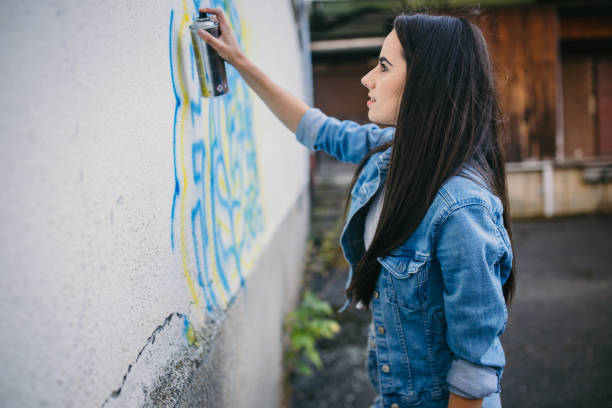istock Young woman painting graffiti with spray paint on wall 1372307851