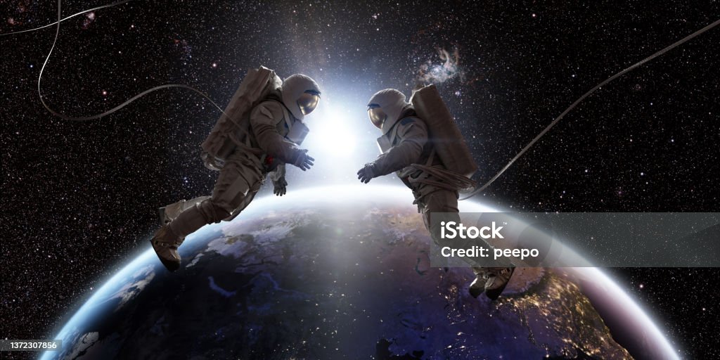 Two Astronauts In Space Facing Each Other In Front Of Earth Two astronauts in full spacesuits with backpacks on a space walk with tethers, facing each other with hands out. They are floating in the front of Planet Earth as the sun rises between them. 

Background images credit: NASA https://eoimages.gsfc.nasa.gov/images/imagerecords/90000/90008/europe_vir_2016_lrg.png and ESO Astronaut Stock Photo