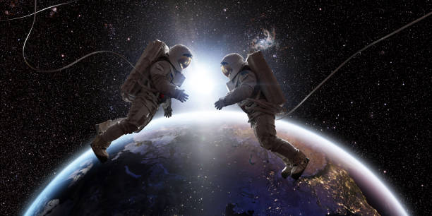 Two Astronauts In Space Facing Each Other In Front Of Earth Two astronauts in full spacesuits with backpacks on a space walk with tethers, facing each other with hands out. They are floating in the front of Planet Earth as the sun rises between them. 

Background images credit: NASA https://eoimages.gsfc.nasa.gov/images/imagerecords/90000/90008/europe_vir_2016_lrg.png and ESO astronaut stock pictures, royalty-free photos & images