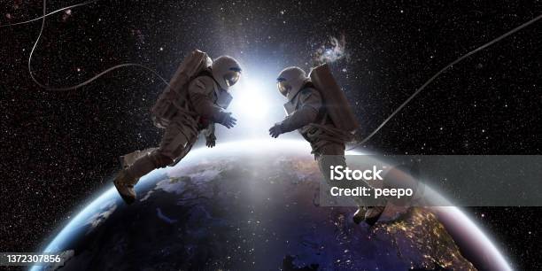 Two Astronauts In Space Facing Each Other In Front Of Earth Stock Photo - Download Image Now