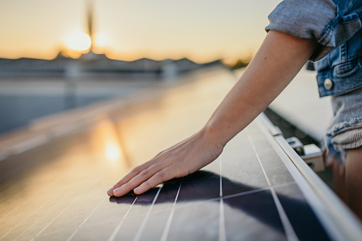 Young woman hands touching solar panels at power station against sky