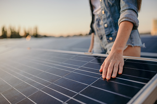 Young woman in hot pants touching solar panels at power station