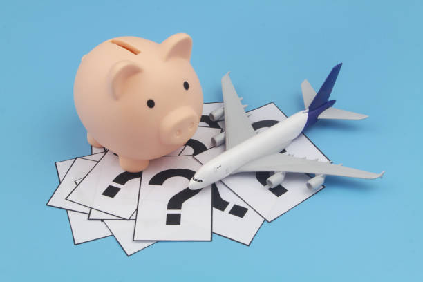 istock Airplane model, question marks and piggy bank on blue background. 1372307989