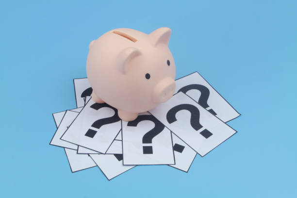 istock Piggy bank on and question marks on blue background. 1372308050