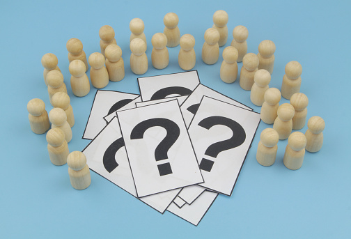 Question and answers of people and faq concept. Wooden people figures around question marks on blue background.