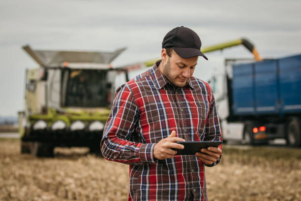 istock Farmer controlling harvest processes with his tablet, standing, combine harvester in the background 1372314030