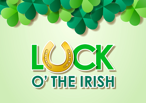 Typography of Luck O' The Irish with horseshoes to celebrate St. Patrick's Day on the green shamrocks background