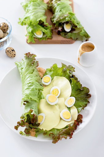 Lettuce, cheese, quail egg are served on a plate for rolling.