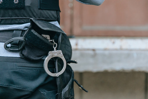 Handcuffs hanging from policeman duty belt.