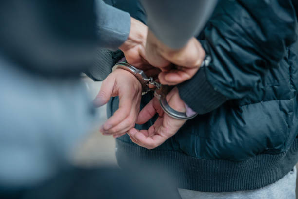 Policeman unlocking a handcuffs on the criminal's back stock photo