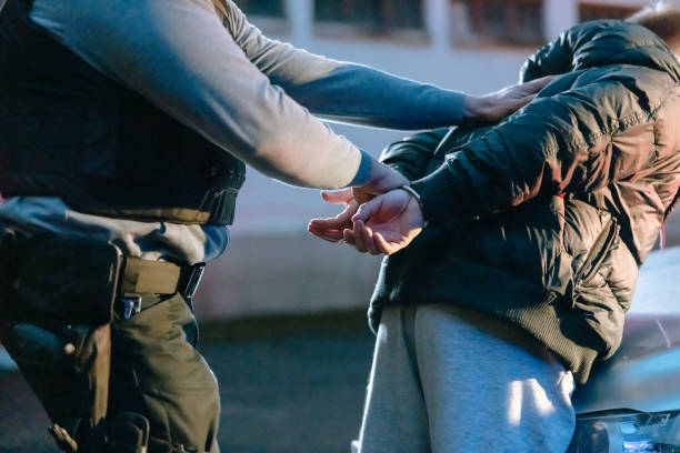 istock Policeman putting a handcuffs on suspect's hands and leaning him on the car 1372320057