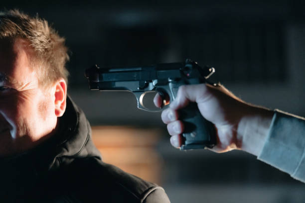 istock Unrecognizable person aiming a gun to a smiling man 1372320583