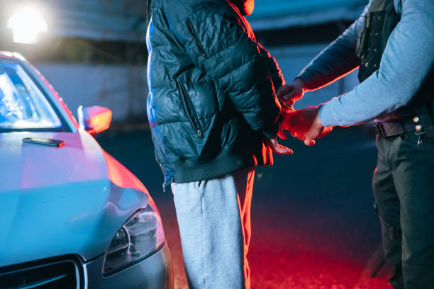 istock Policeman putting a handcuffs on suspect's hands by the car 1372320619