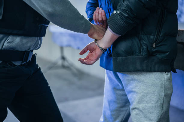 Policeman putting a handcuffs on criminal's hands stock photo