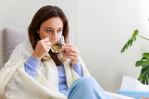 Woman drinking herb tea Young woman feeling sick drinking herbal tea Sore Throat no Fever stock pictures, royalty-free photos & images