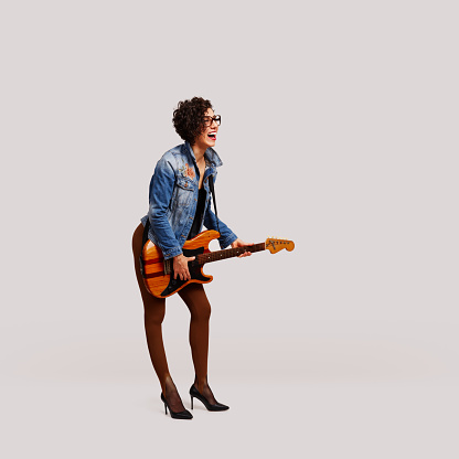 Cheerful female rock musician enjoys the music with electric guitar on white background