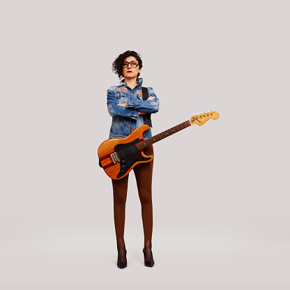 Female rock musician with electric guitar posing on white background