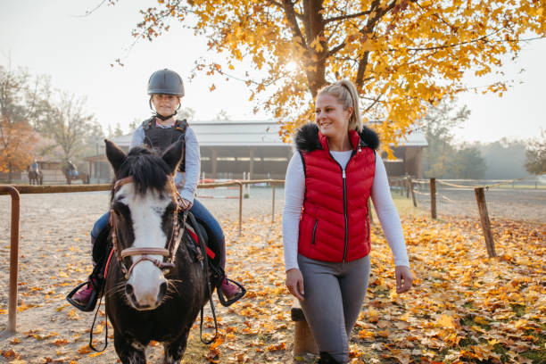 madre che insegna a sua figlia l'equitazione - teaching child horseback riding horse foto e immagini stock