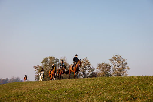 Group of horse riders riding horses on rural landscape