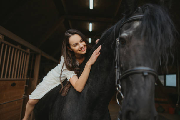 istock Young woman smiling and stroking while lying on horseback 1372323561