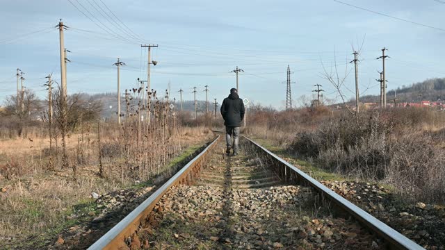 A man is walking on the railway. Filmed from behind.