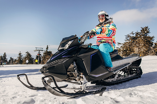 Mature man driving a snowmobile on mountain on winter day.