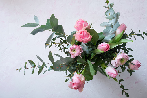 Spring bouquet with beautiful pink flowers and eucalyptus on bright background. Top view phtography.