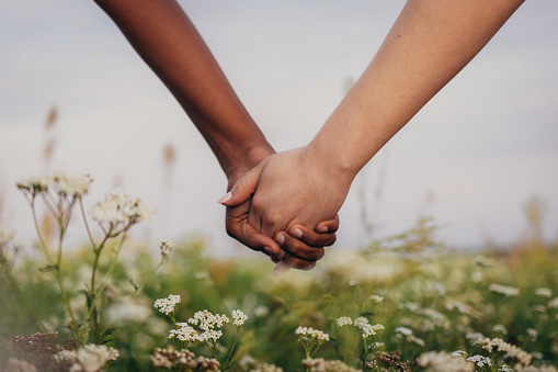 Close up of multi-ethnic couple women holding hands on field