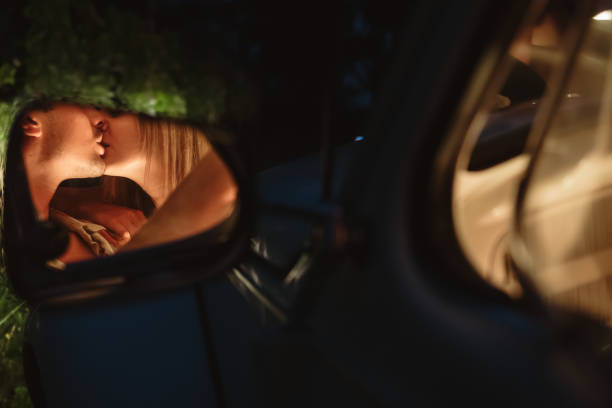 młoda para całująca się odbijająca w bocznym lusterku samochodu - mirror women kissing human face zdjęcia i obrazy z banku zdjęć