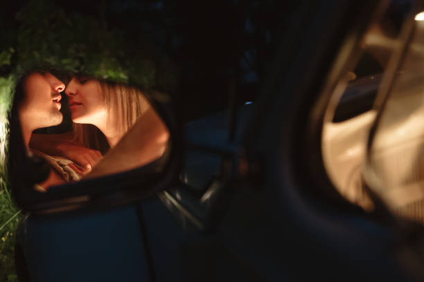 jovem casal se beija refletindo no espelho de vista lateral do carro - mirror women kissing human face - fotografias e filmes do acervo