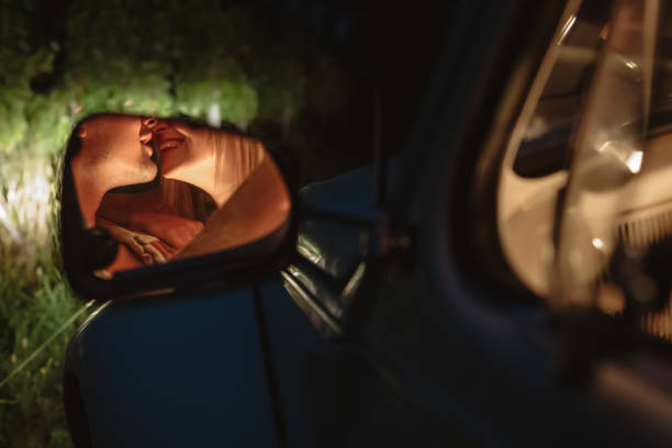 jovem casal se beija refletindo no espelho de vista lateral do carro - mirror women kissing human face - fotografias e filmes do acervo