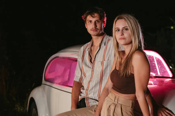 istock Young couple standing beside car in field 1372330813