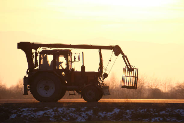 Mobile lifting crane tractor driving on intercity road at sunset.