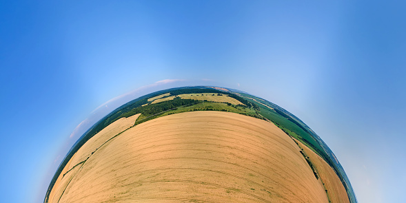 Aerial view from high altitude of little planet earth with yellow cultivated agricultural field with ripe wheat on bright summer day.