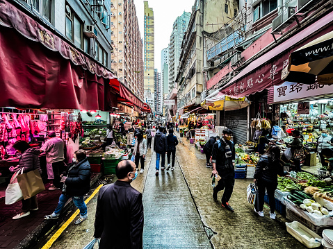 Hong Kong, China - February 3, 2022: People wearing masks are seen beside Wan Chai Food Street market amid the coronavirus outbreak on February 2022 in Hong Kong, China.