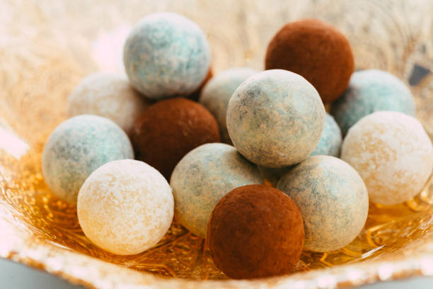 Macro close up color image depicting a heap of mint chocolate truffles in an elegant gold dish. The chocolates are spherical in shape. Selective focus with room for copy space.