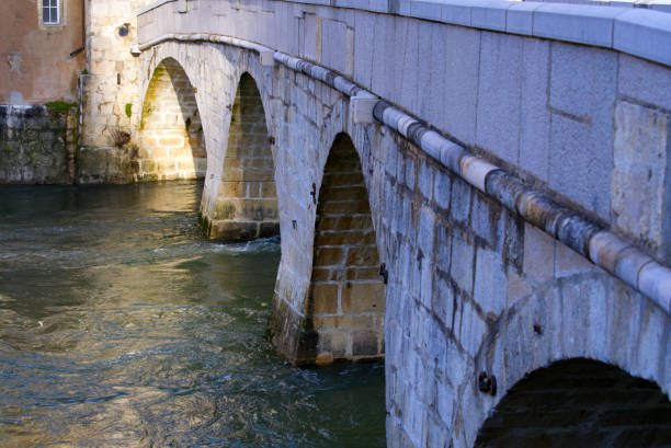 крупным планом мелового каменного моста через реку ду в маленьком средневековом городке сен-урсанна, кантон юра, солнечным зимним утром. - doubs river стоковые фото и изображения