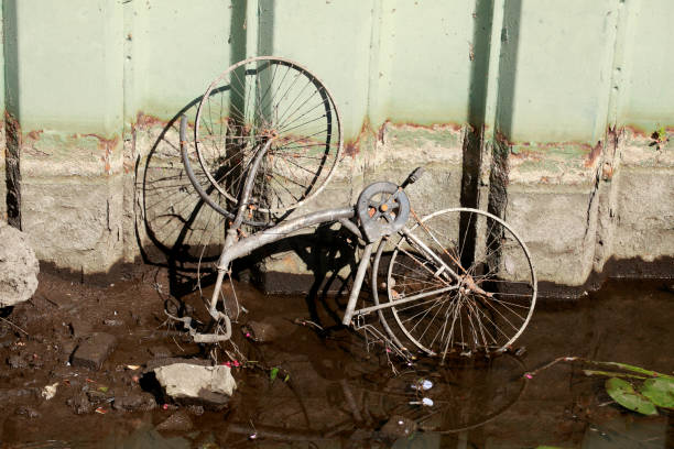 vecchia bici arrugginita sdraiata in un letto del fiume - vergessen foto e immagini stock