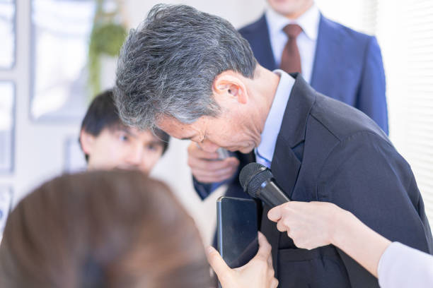 a vip surrounded by the media at an apology meeting - young adult reading newspaper the media imagens e fotografias de stock